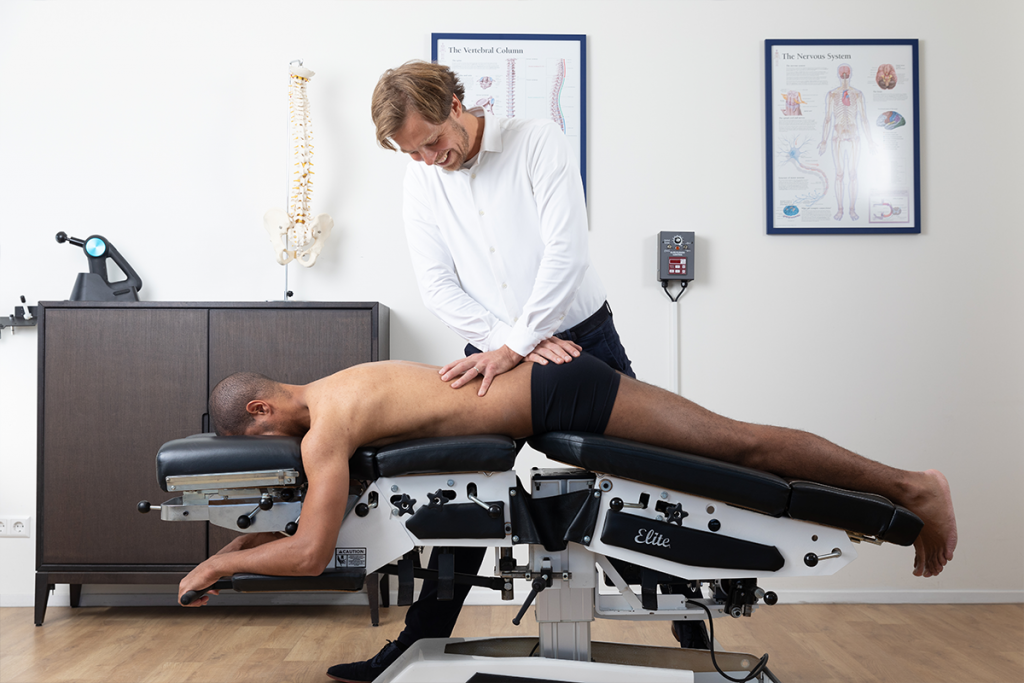 Chiropractor behandelt de onderrug op de behandeltafel: behandeltafels op maat bij hernia